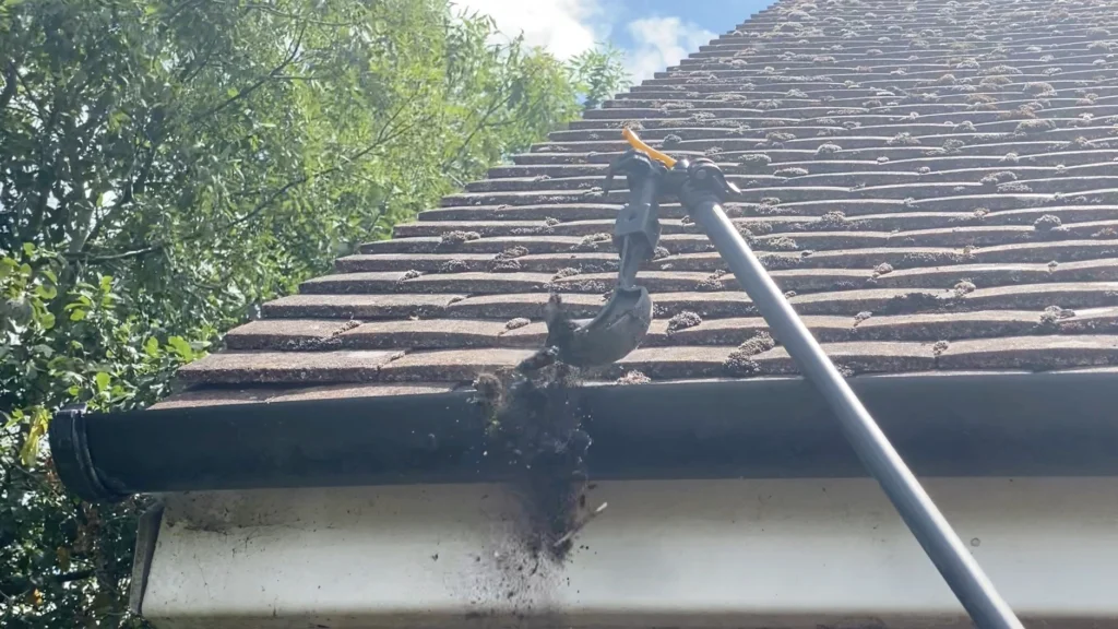 Gutter cleaning in Haringey removing leaves and debris from a residential gutter using a specialist scraper tool