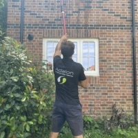 Home Adalon Window Cleaning technician using a water-fed pole to clean first-floor windows in Enfield.