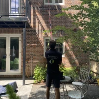 Home Adalon Window Cleaning technician using a water-fed pole to clean high first-floor windows in Enfield.