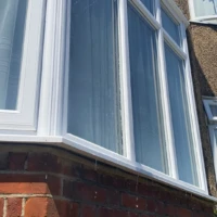 Home Pure water window cleaning with a water-fed pole rinsing ground-floor bay windows in Winchmore Hill.