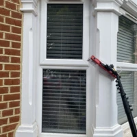Home Water-fed pole brush rinsing ground-floor bay windows during a window cleaning service in Muswell Hill.